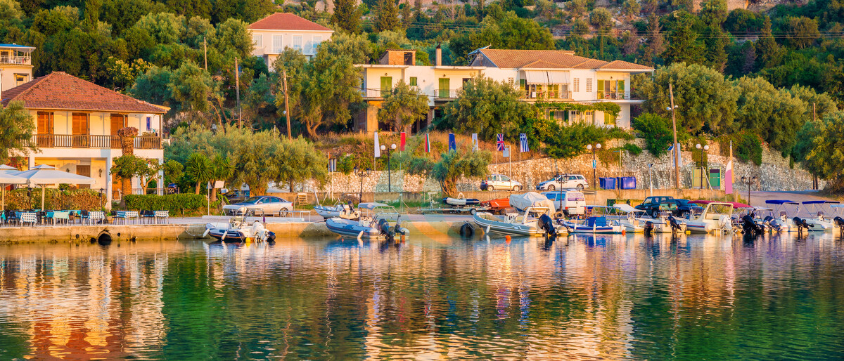 Traditionelle griechische Architektur und Boote im Licht des Sonnenaufgangs am Strand von Nikiana auf der griechischen Insel Lefkada