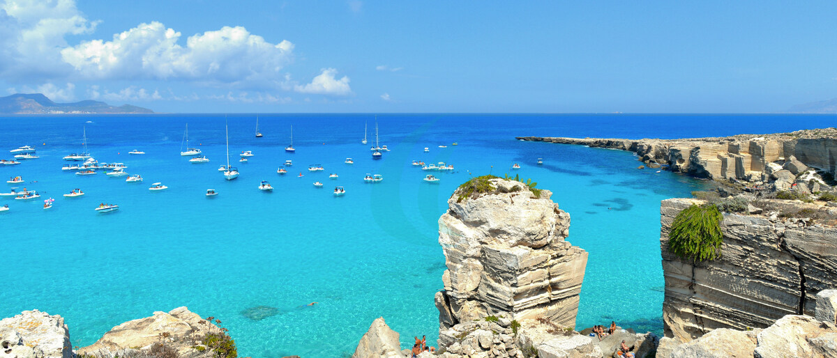 Strand Cala Rossa auf der Insel Favignana mit kleinen Booten und der Insel Marettimo im Hintergrund, Sizilien, Italien
