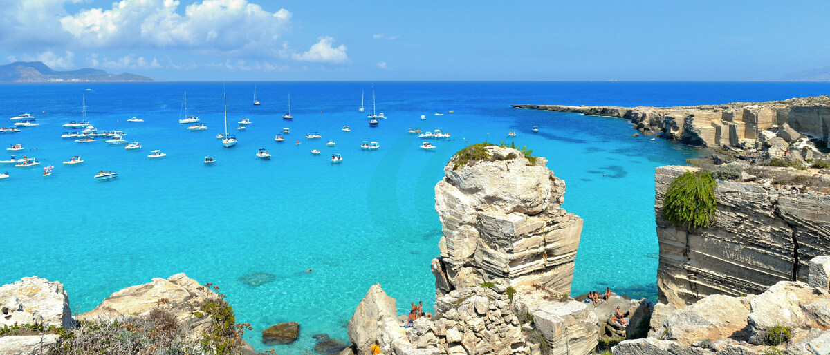 Strand Cala Rossa auf der Insel Favignana mit kleinen Booten und der Insel Marettimo im Hintergrund, Sizilien, Italien