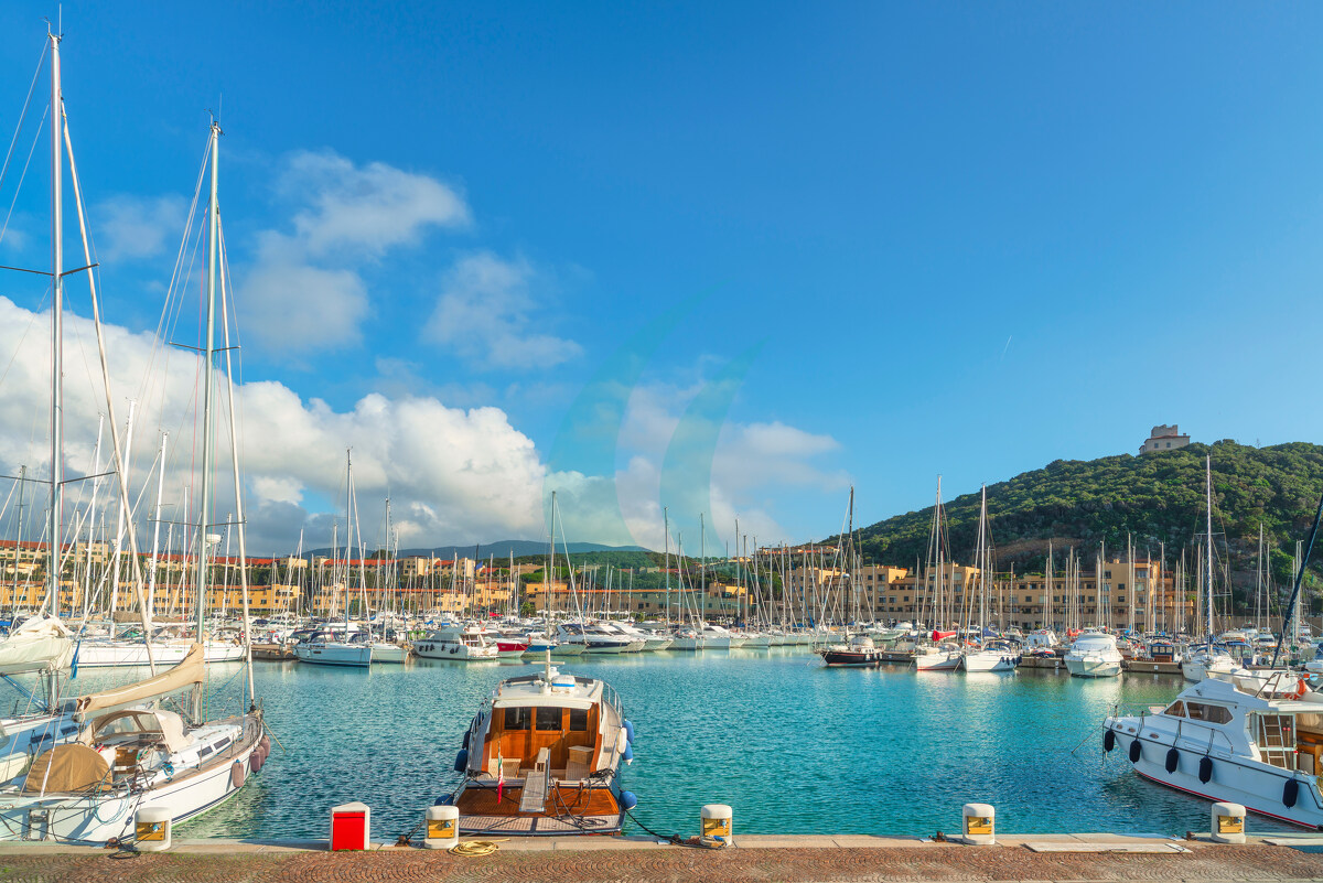 Blick auf Luxusyachten, Motorboote und Segelboote, die im Jachthafen von Punta Ala mit dem Turm auf dem Hügel vor Anker liegen. Grosseto, Toskana, Italien