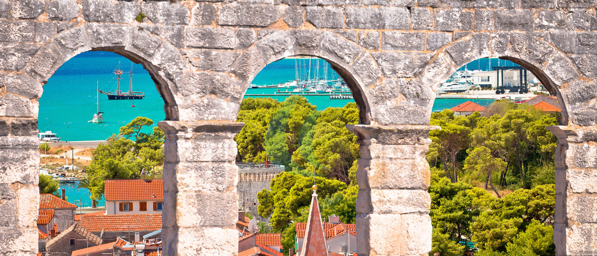 Dächer der Altstadt von Trogir und Blick auf das türkisfarbene Archipel durch steinerne Fenster, Region Dalmatien, Kroatien