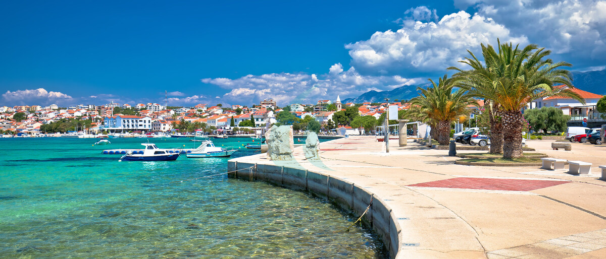 Panoramablick auf die Uferpromenade der Stadt Novalja und das türkisfarbene Meer auf der Insel Pag im Adriatischen Archipel Kroatiens