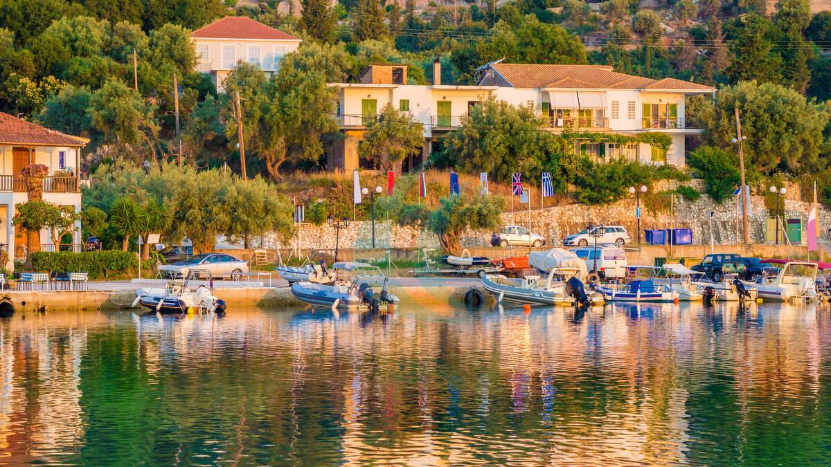 Traditionelle griechische Architektur und Boote im Licht des Sonnenaufgangs am Strand von Nikiana auf der griechischen Insel Lefkada