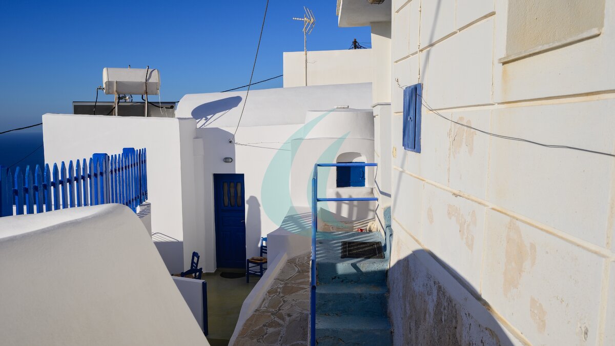 Enge Gasse zwischen weiß gekalkten Häusern mit blauen Türen und Geländern in Anafis Chora