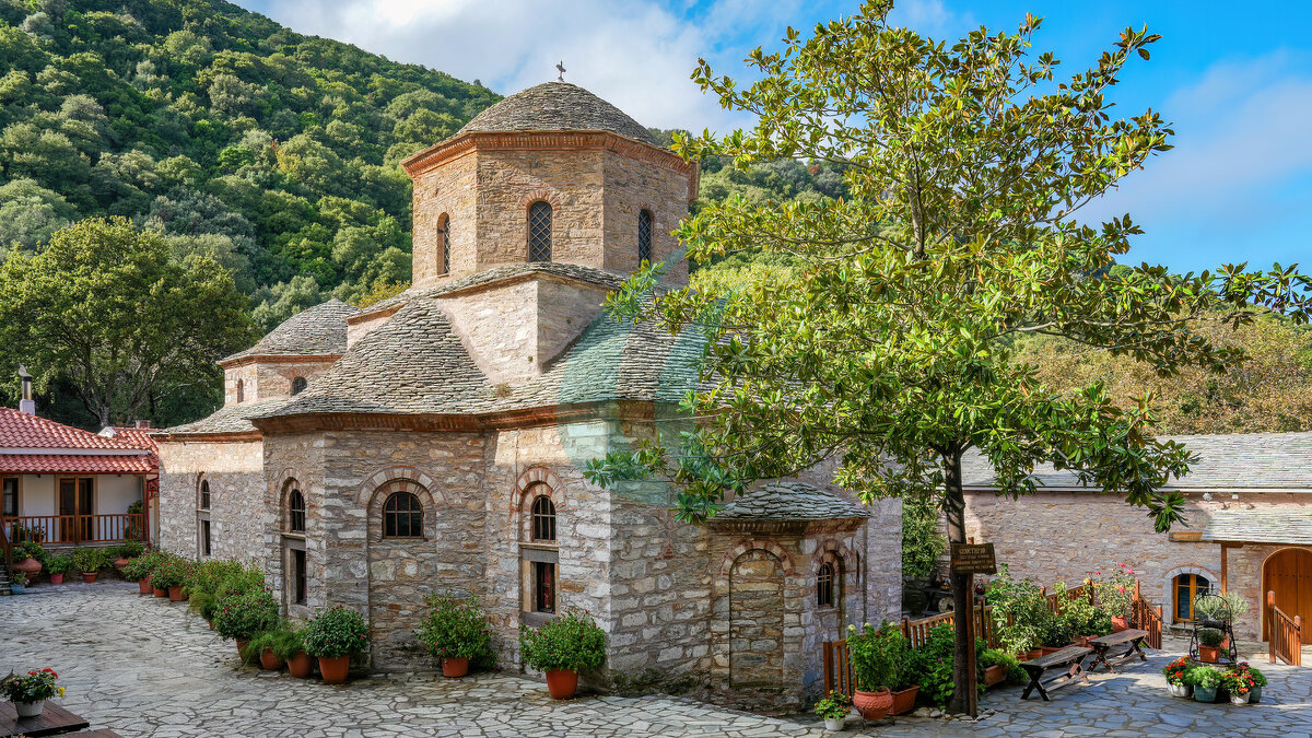 Steinerne Klosterkirche Evangelistria auf Skiathos zwischen Bäumen und Hofgebäuden